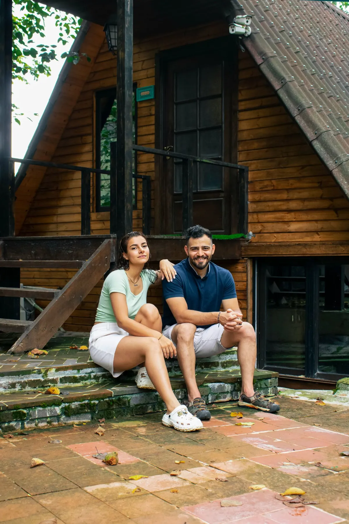 Un couple assis sur les marches d'une maison en bois.